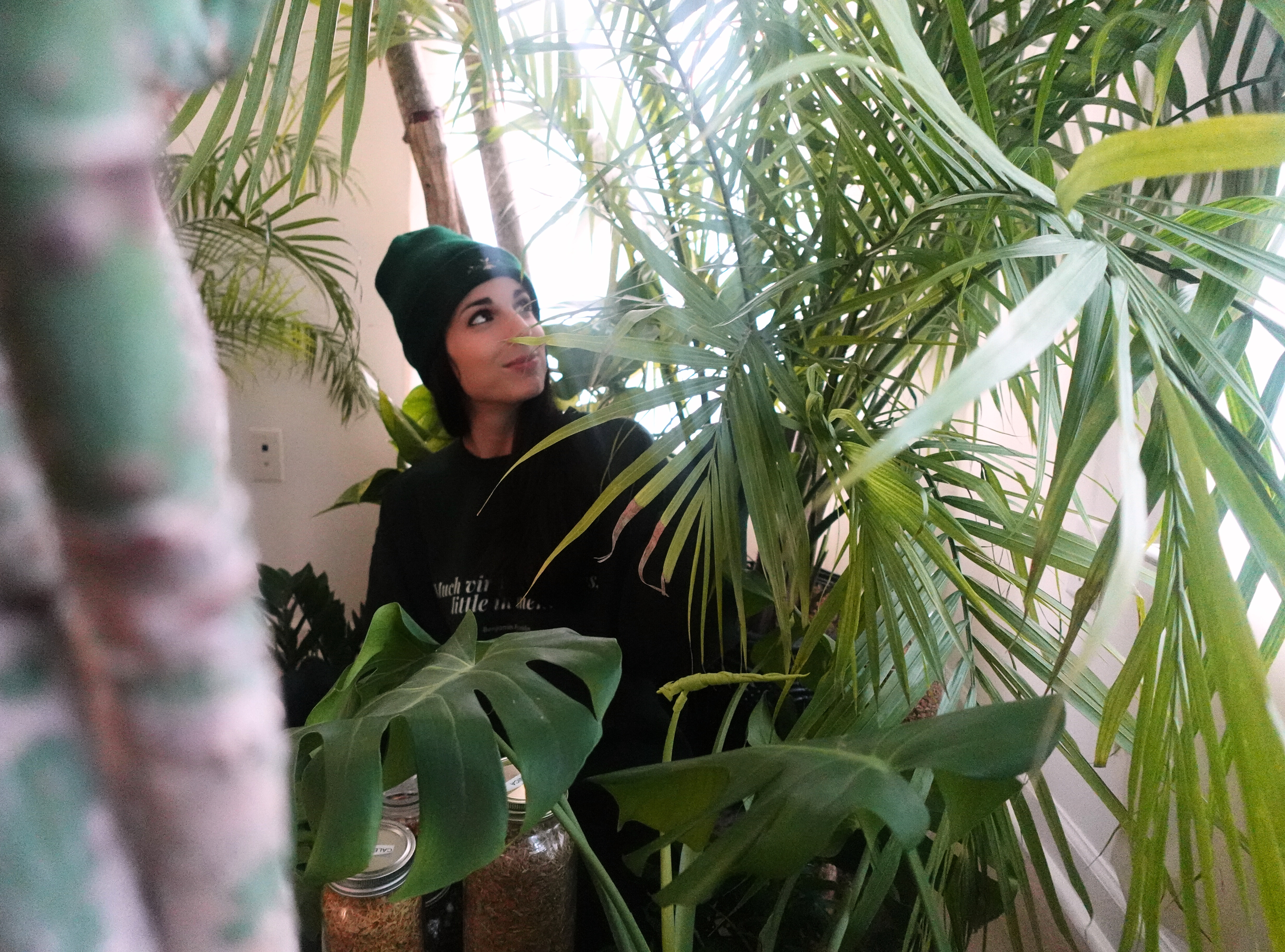 Nic wearing a hat, gazing artfully at a cluster of plants.