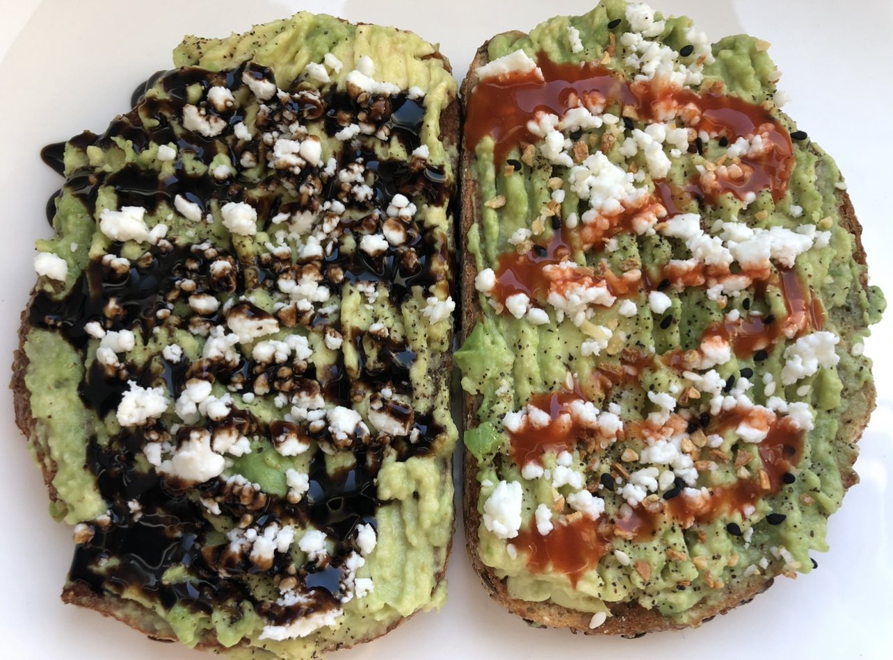 Two slices of toast topped with creamy avocado and herbs.