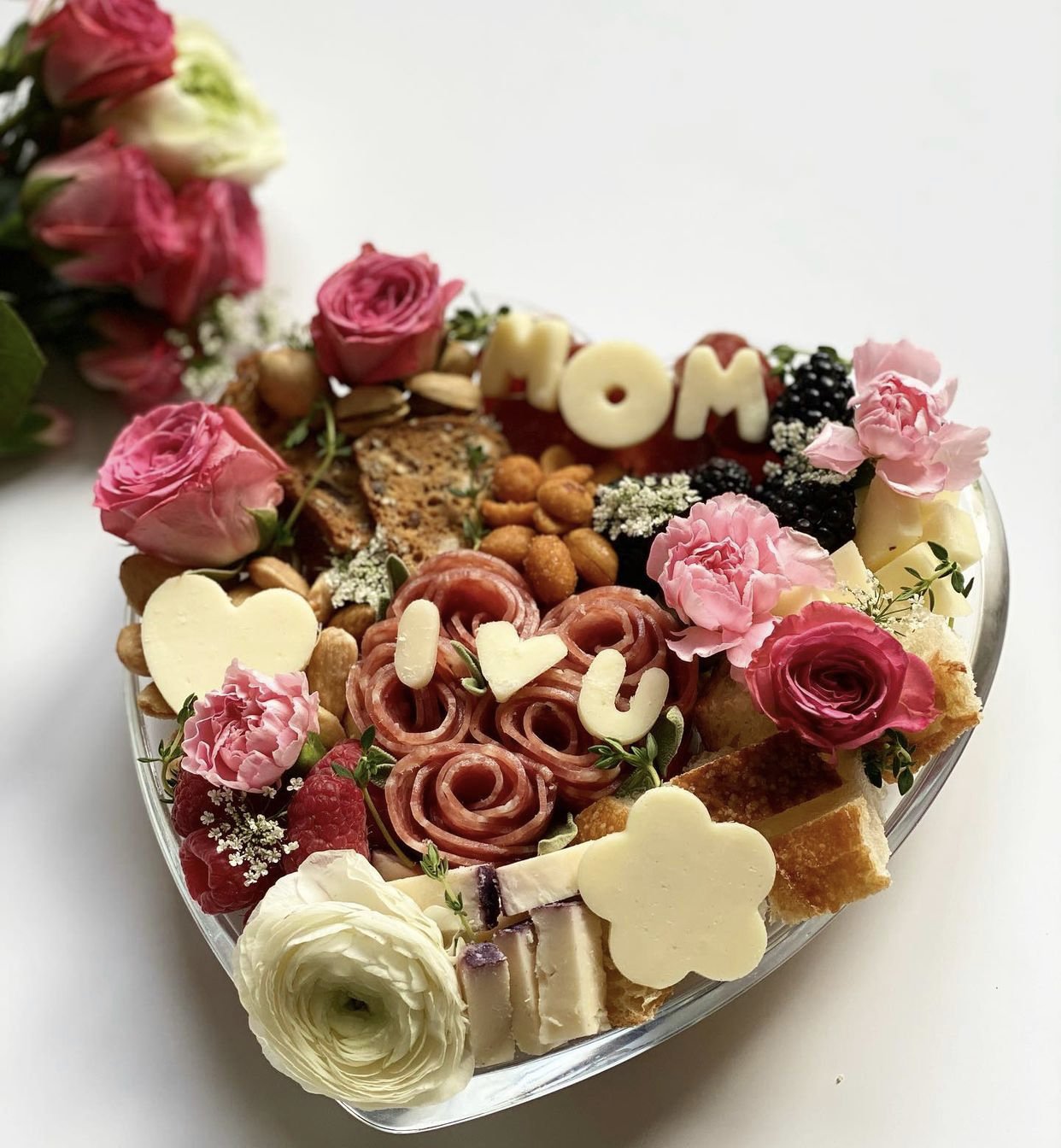 A Mother’s Day-themed charcuterie board with flowers and sweets.