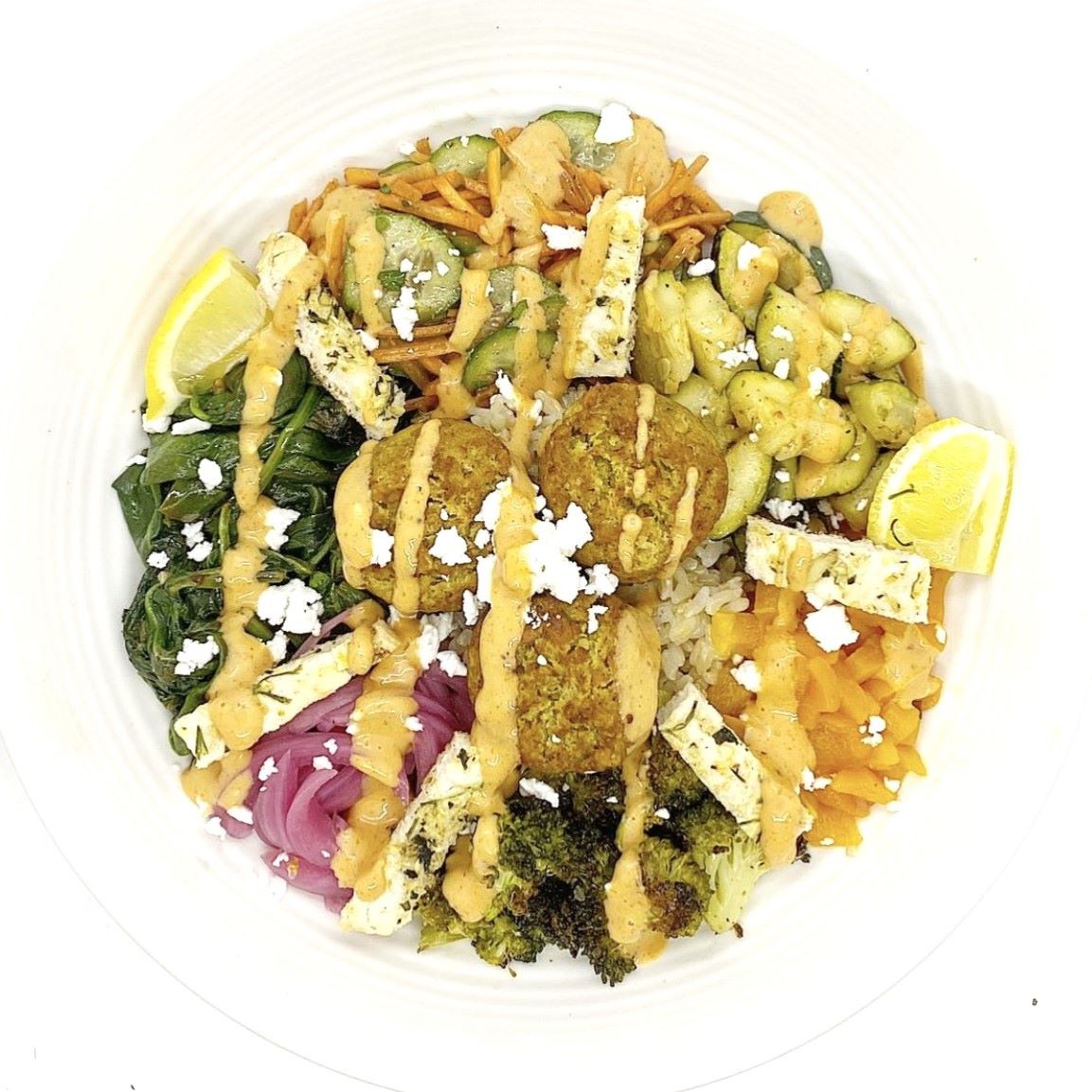 A bowl of spinach falafel with lemony broccoli and grains.